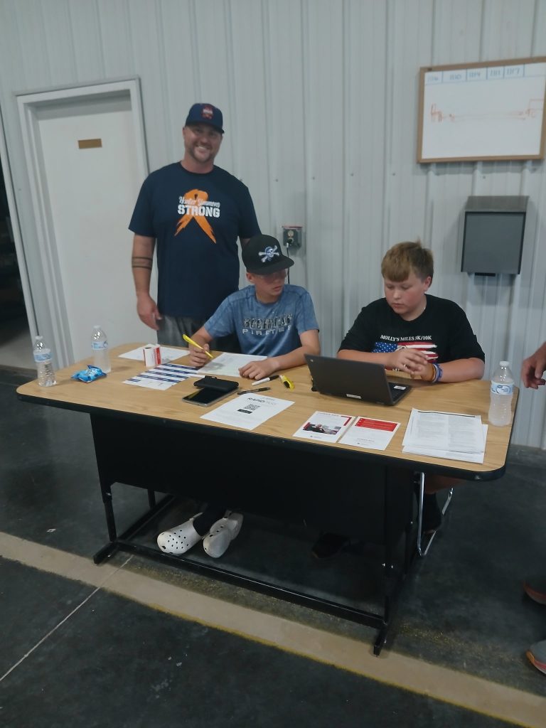 Hunter Simmons, seated on left, helps check people in during the Guns and Hoses Blood Drive held in his honor. Photo by Elizabeth Davis